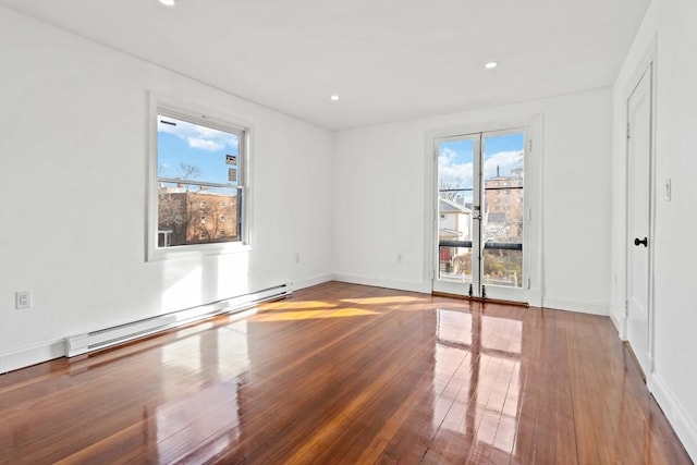 unfurnished room with wood-type flooring and a baseboard heating unit