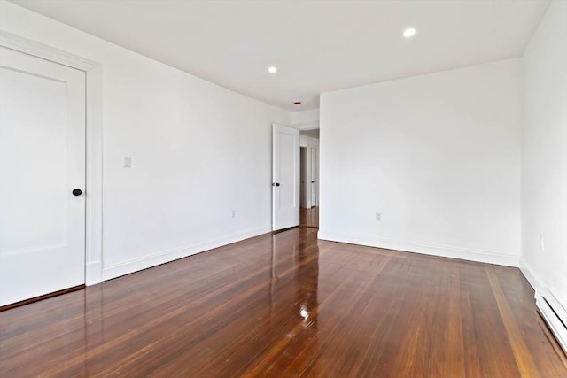 spare room with a baseboard radiator and dark hardwood / wood-style floors