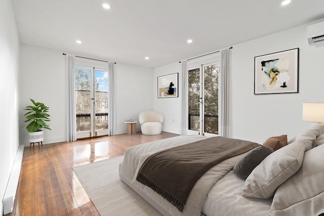 bedroom featuring light wood-type flooring, access to outside, and a wall mounted AC