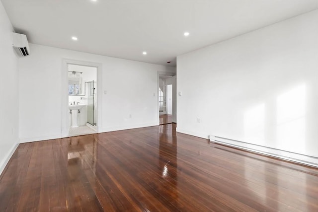 empty room with hardwood / wood-style flooring, a baseboard radiator, and a wall mounted AC