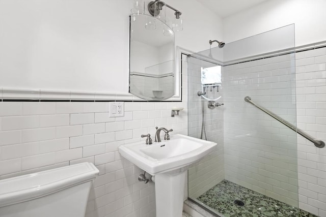 bathroom featuring sink, toilet, tile walls, and a tile shower