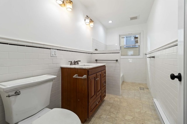 bathroom featuring vanity, toilet, tile walls, and a bathing tub