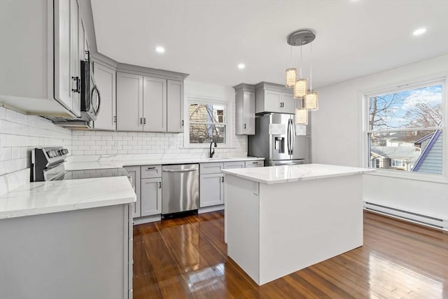 kitchen with baseboard heating, gray cabinets, a kitchen island, and stainless steel appliances