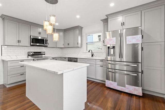 kitchen with pendant lighting, a center island, sink, light stone countertops, and appliances with stainless steel finishes