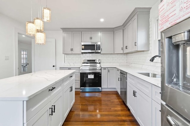 kitchen featuring sink, dark wood-type flooring, light stone counters, decorative backsplash, and appliances with stainless steel finishes