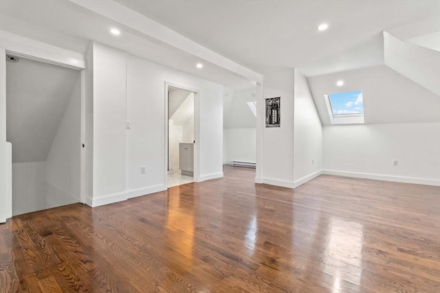 additional living space featuring hardwood / wood-style floors, lofted ceiling with skylight, and a baseboard radiator