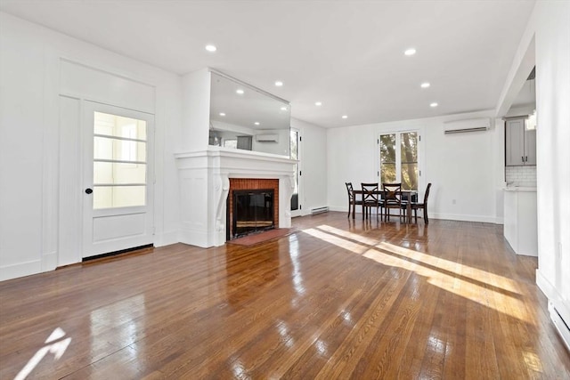 unfurnished living room featuring hardwood / wood-style floors and a wall mounted AC