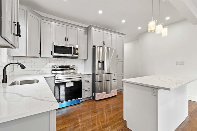 kitchen with light stone countertops, sink, a center island, tasteful backsplash, and appliances with stainless steel finishes