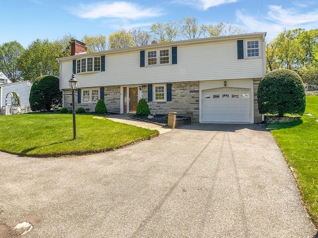 view of front of home with aphalt driveway, an attached garage, stone siding, a front lawn, and a chimney