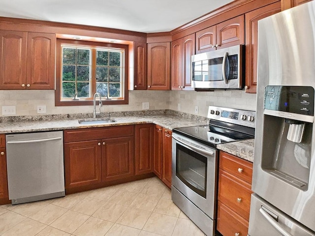 kitchen featuring a sink, brown cabinetry, light tile patterned flooring, backsplash, and appliances with stainless steel finishes