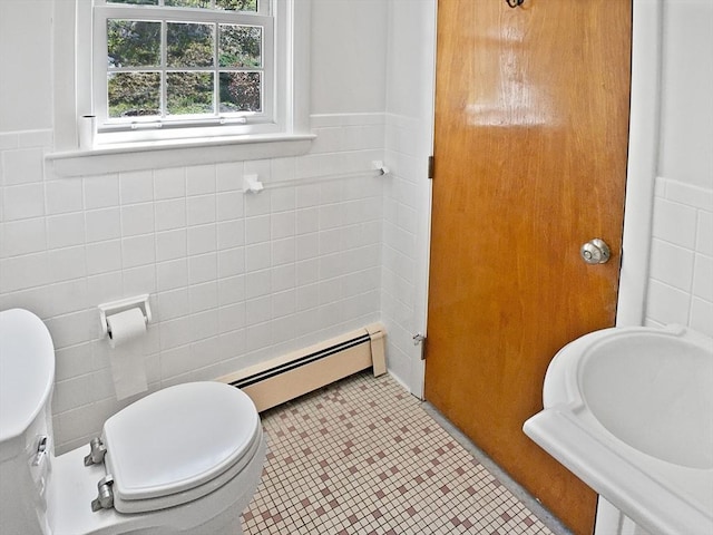 half bath featuring wainscoting, tile walls, toilet, and a baseboard heating unit