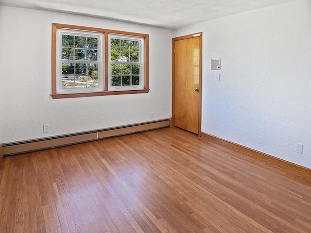 spare room with baseboards, a baseboard radiator, and light wood finished floors