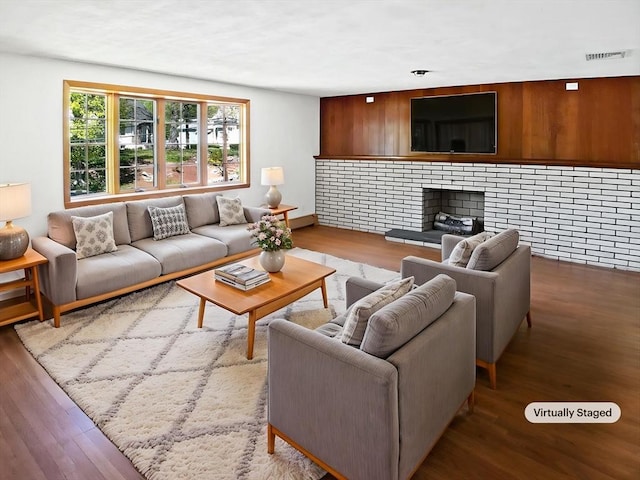 living area featuring a fireplace, visible vents, and wood finished floors