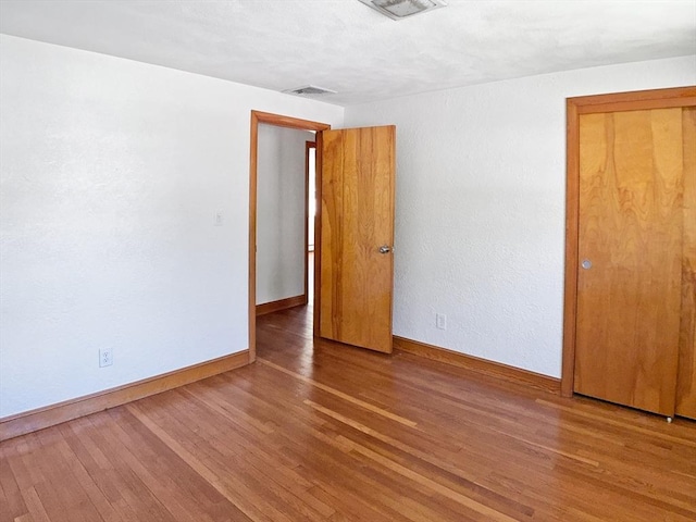 spare room with baseboards, visible vents, and wood finished floors