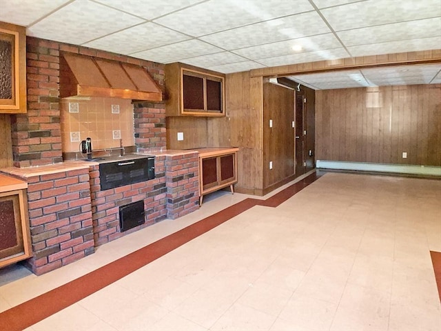interior space featuring a drop ceiling, tile patterned floors, and wood walls