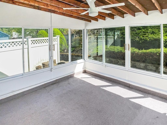 unfurnished sunroom with a ceiling fan and beam ceiling