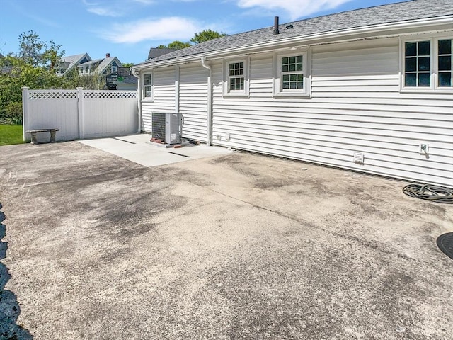 rear view of property with central AC unit, a patio area, and fence