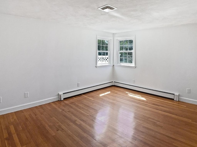 spare room featuring baseboards, a baseboard radiator, and wood finished floors