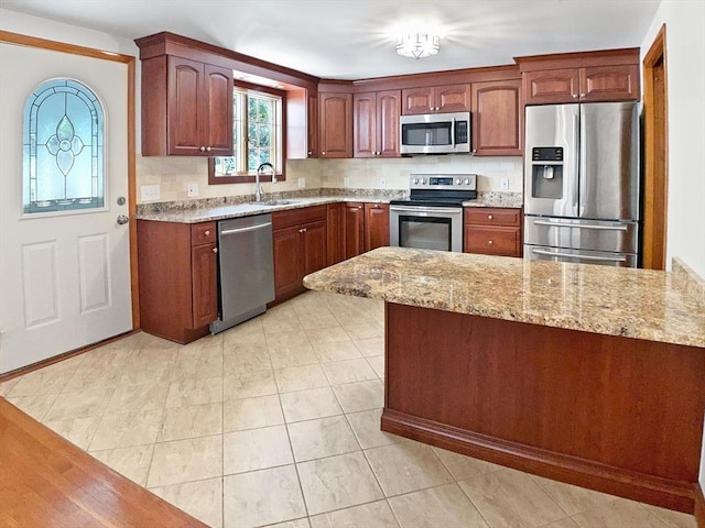 kitchen featuring a sink, a peninsula, stainless steel appliances, and light stone countertops