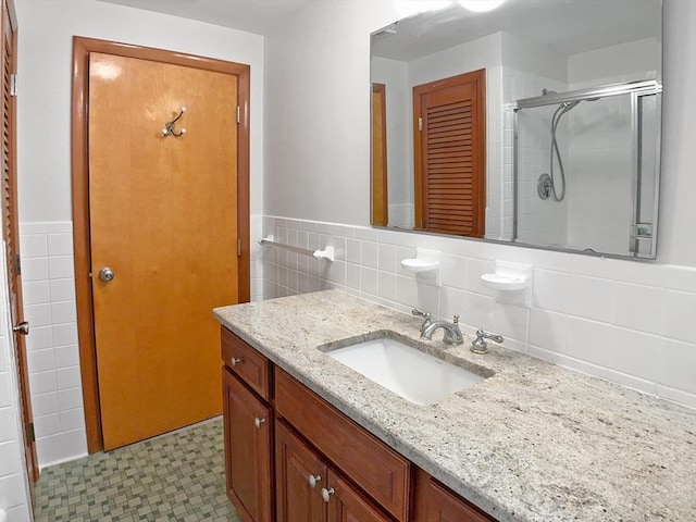 full bath featuring tile walls, vanity, a shower stall, and a wainscoted wall