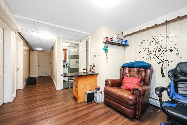 living area with dark wood-type flooring and a paneled ceiling