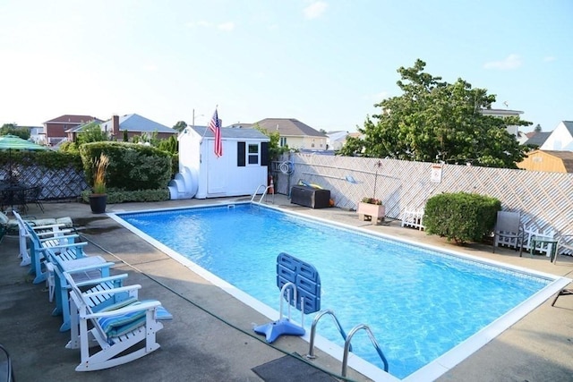 view of swimming pool featuring a patio area, fence, a fenced in pool, and an outdoor structure