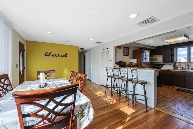 dining space with wood finished floors, visible vents, and recessed lighting