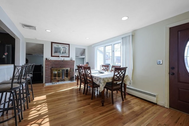 dining area featuring visible vents, wood finished floors, baseboard heating, a brick fireplace, and recessed lighting