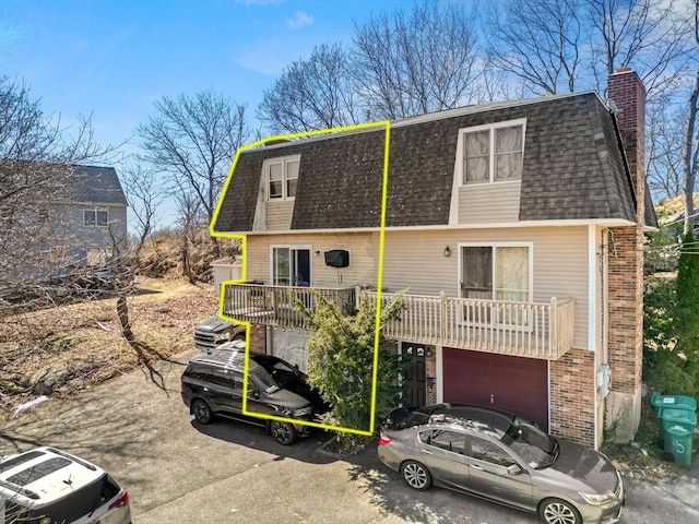 view of front of house featuring brick siding, roof with shingles, mansard roof, a garage, and driveway