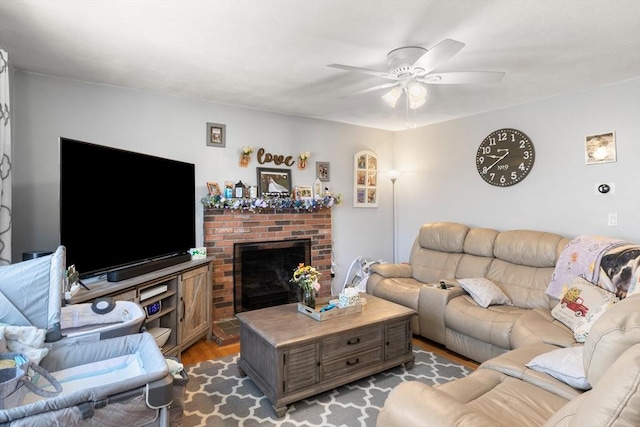 living area with a fireplace, ceiling fan, and wood finished floors