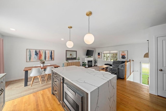 16 Chandler Dr, Marshfield, MA 02050 - kitchen featuring stainless steel microwave, light wood finished floors, pendant lighting, a kitchen island, and light stone counters