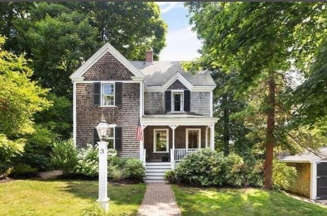 view of front of house with a front lawn, covered porch, and a chimney