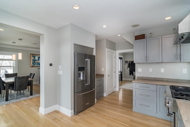 kitchen with wall chimney exhaust hood, recessed lighting, high quality appliances, light wood finished floors, and baseboards