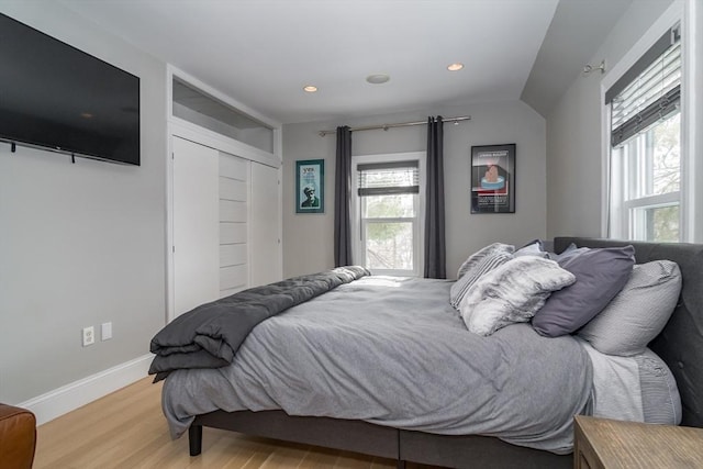 bedroom featuring a closet, recessed lighting, light wood finished floors, and baseboards