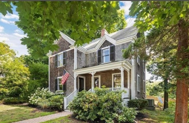 shingle-style home with a porch, central AC, and a chimney