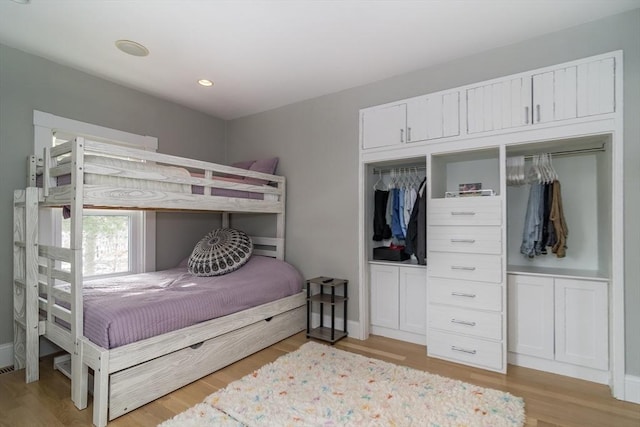 bedroom with a closet, wood finished floors, baseboards, and recessed lighting