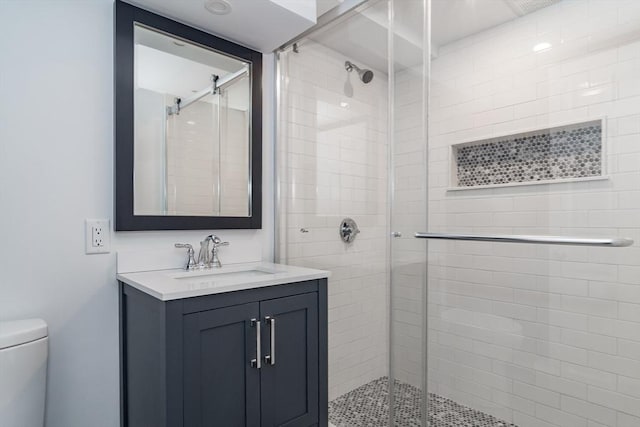 bathroom featuring toilet, a shower stall, and vanity