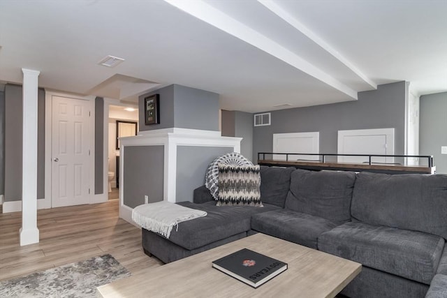 living room featuring light wood-style floors, baseboards, and visible vents