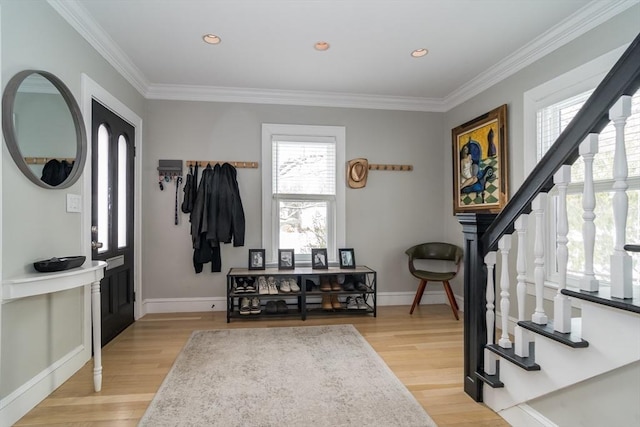 foyer entrance featuring stairs, light wood finished floors, baseboards, and crown molding