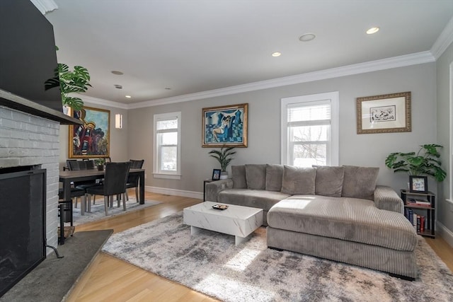 living room featuring baseboards, a brick fireplace, crown molding, recessed lighting, and wood finished floors