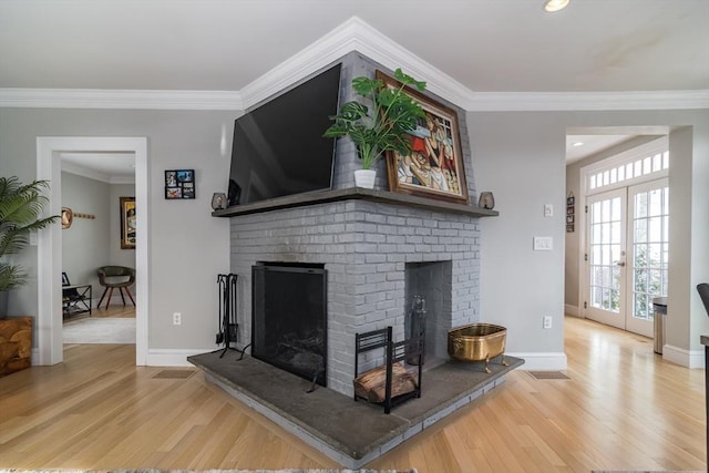 living area with crown molding, baseboards, wood finished floors, and a brick fireplace
