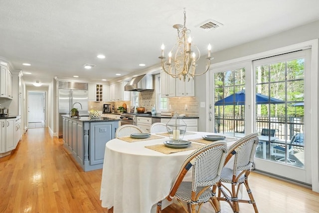 dining space with visible vents, recessed lighting, light wood-style flooring, and a notable chandelier