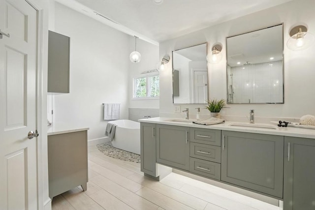 full bathroom with double vanity, a freestanding tub, a shower stall, and a sink