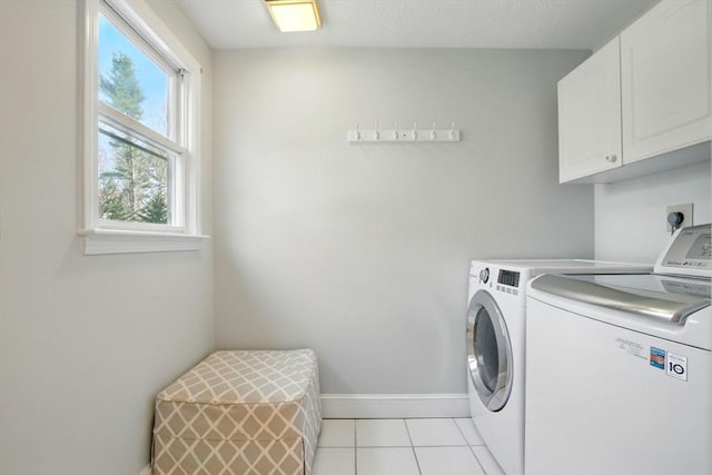 clothes washing area with baseboards, washer and clothes dryer, cabinet space, and light tile patterned flooring