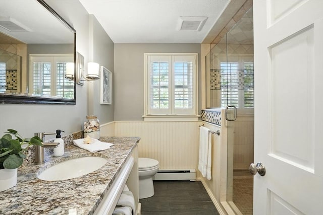 full bath featuring wainscoting, a shower stall, vanity, a baseboard heating unit, and toilet