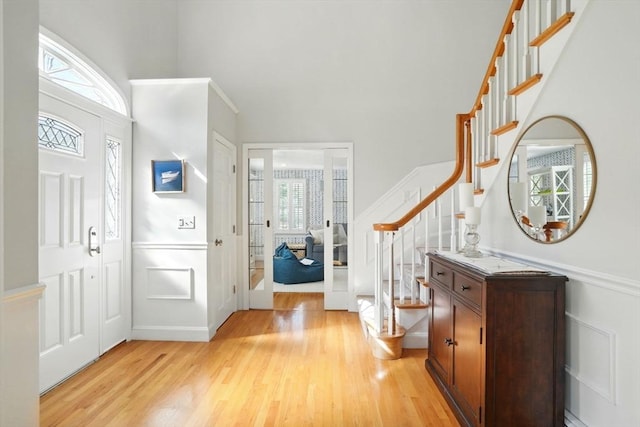 entrance foyer with wainscoting, light wood-style flooring, and stairway
