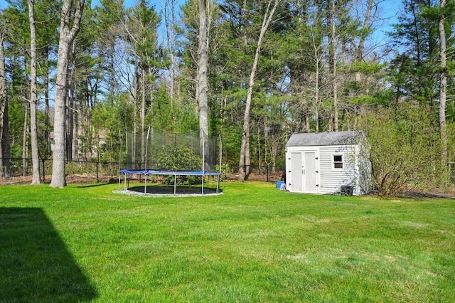 view of yard with a storage shed, fence, an outdoor structure, and a trampoline