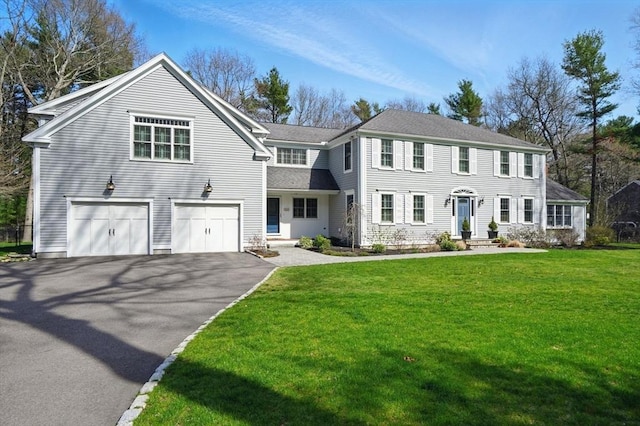 view of front facade with a shingled roof, an attached garage, a front lawn, and aphalt driveway
