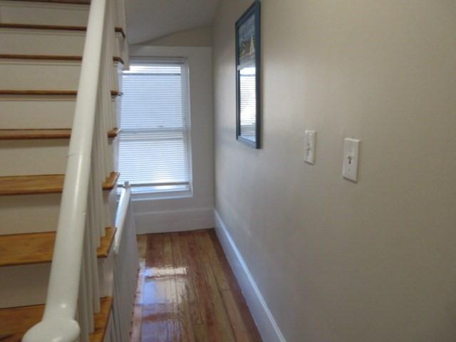 hallway with hardwood / wood-style floors, stairway, and baseboards