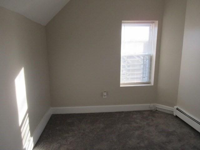 carpeted spare room with baseboard heating, healthy amount of natural light, vaulted ceiling, and baseboards